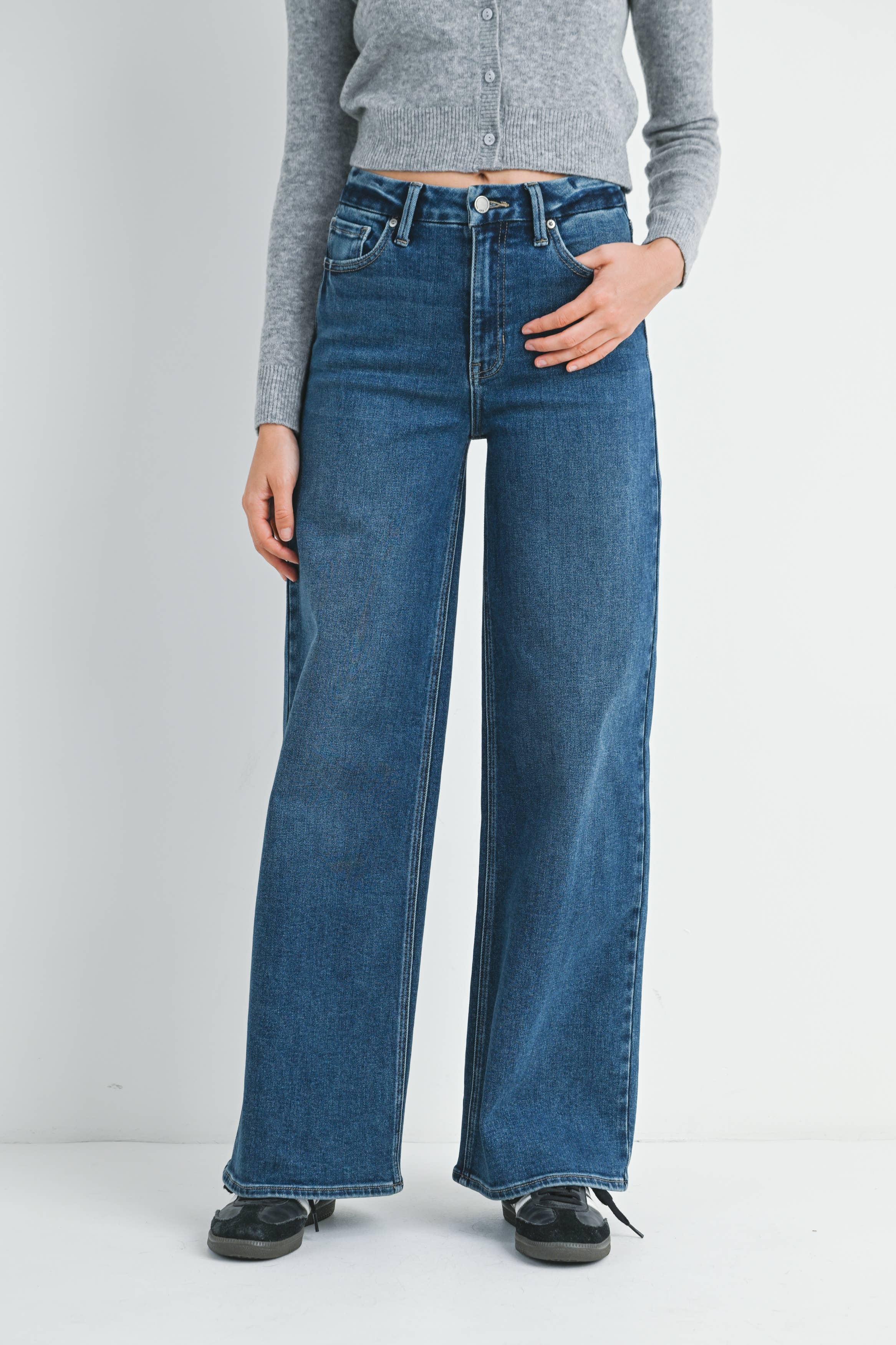Person wearing blue jeans and a gray shirt on a plain background