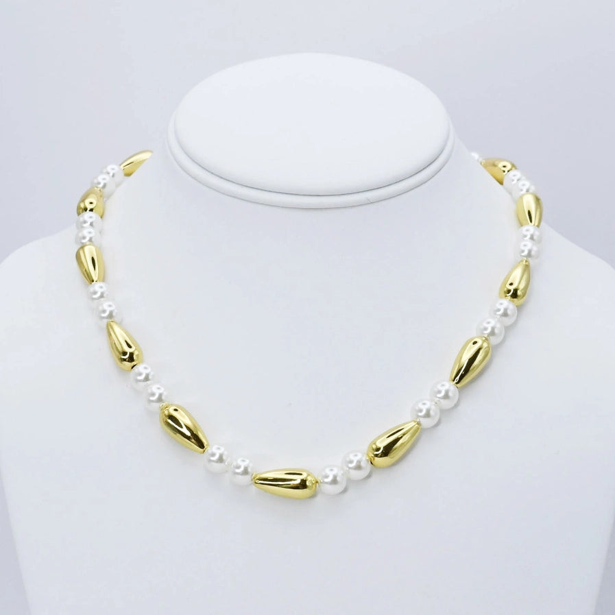 Necklace Featuring soft pearl beads woven with gold accents, this piece is finished with a clear protective coat to preserve its glow over time. At 16 inches with a 2-inch extender.
