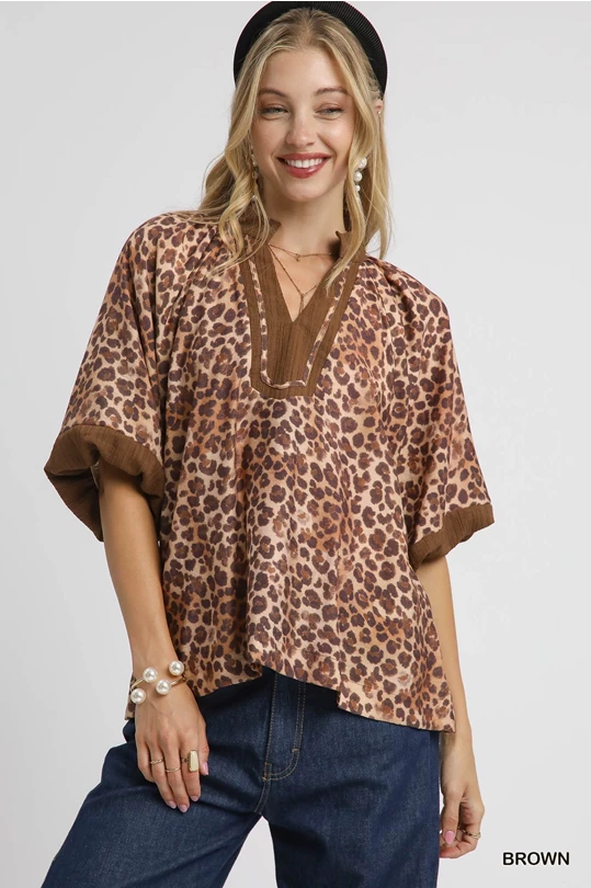 relaxed-fit blouse features a bold leopard print on a silky soft fabric, accented with rich brown ribbed trim at the V-notch neckline and sleeves