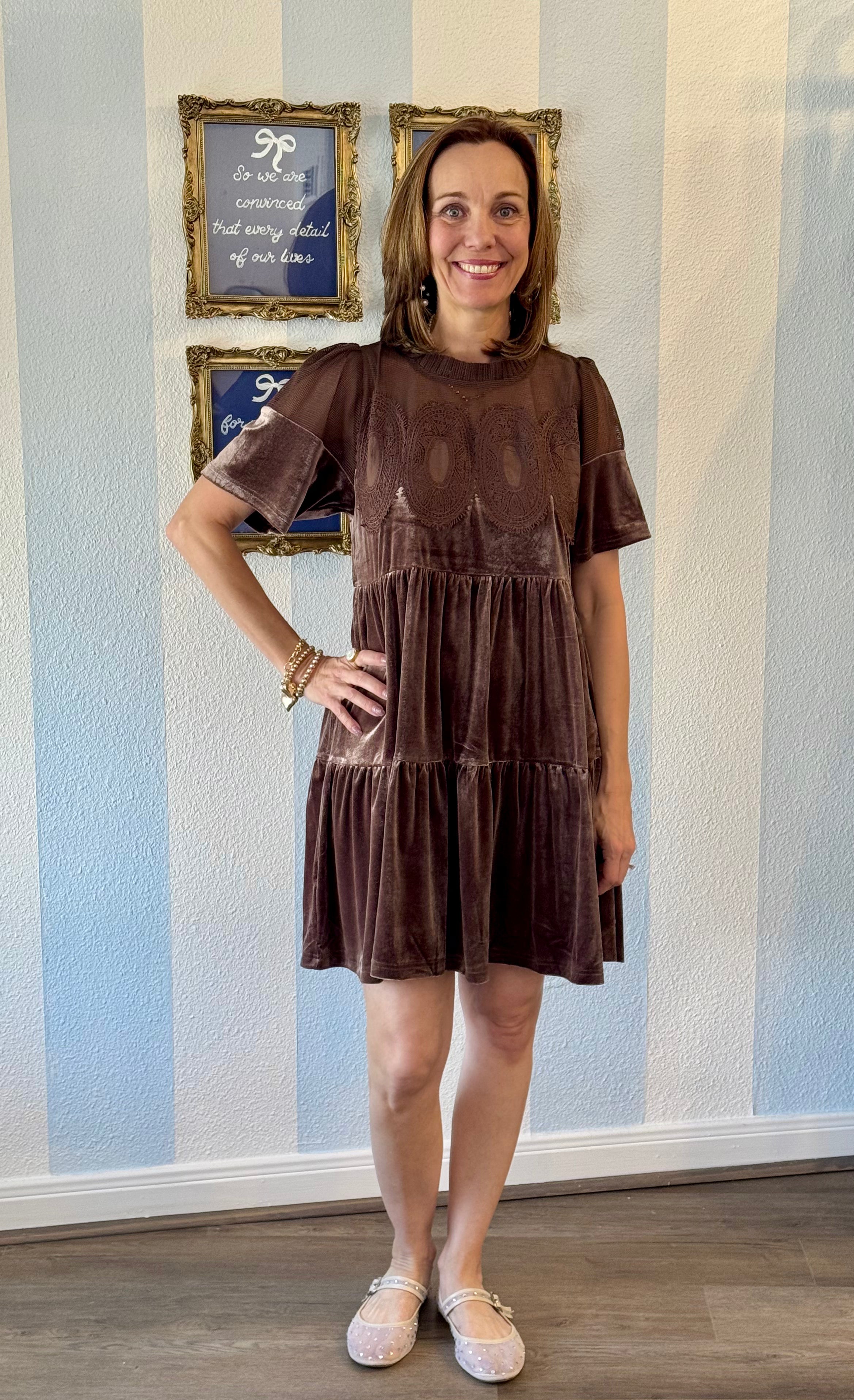 Woman wearing mocha velvet tiered dress with embroidered lace bodice and short sleeves, styled with gold bracelets and blush flats.