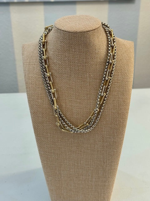 Multi-layered necklace on a beige bust against a neutral background
