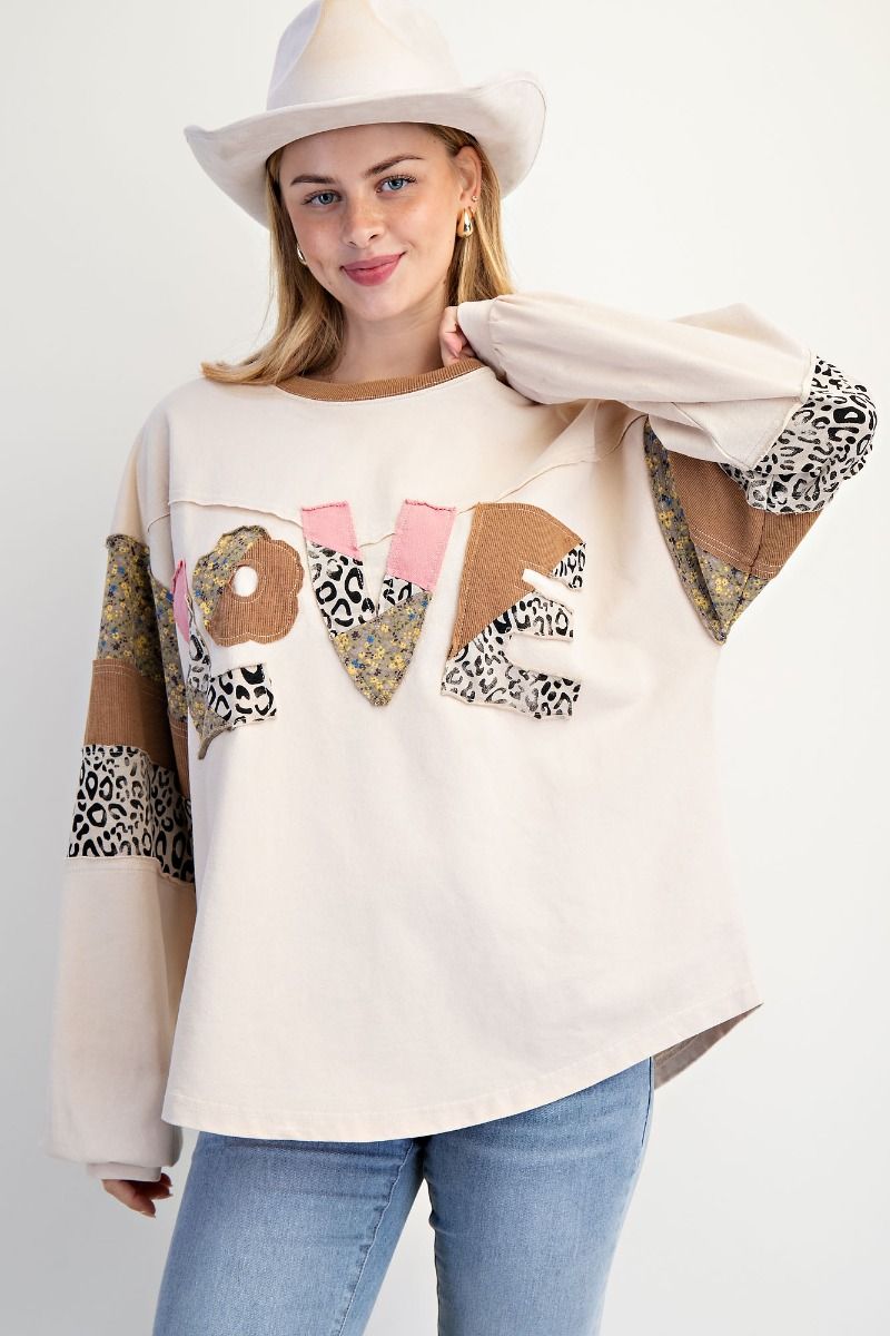 Woman wearing a cream sweater with &