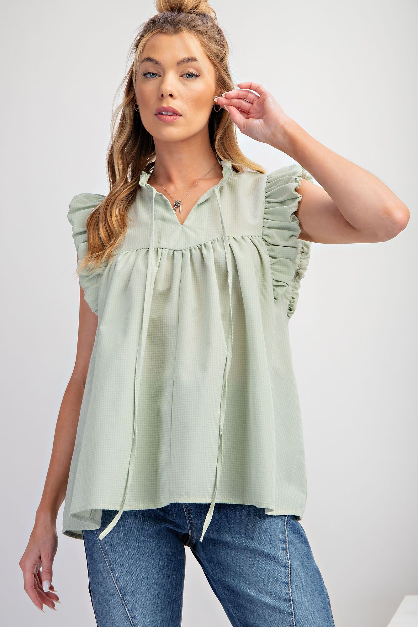 top has a ruffled neckline, front tie, and ruched detailing, all in a green plaid design