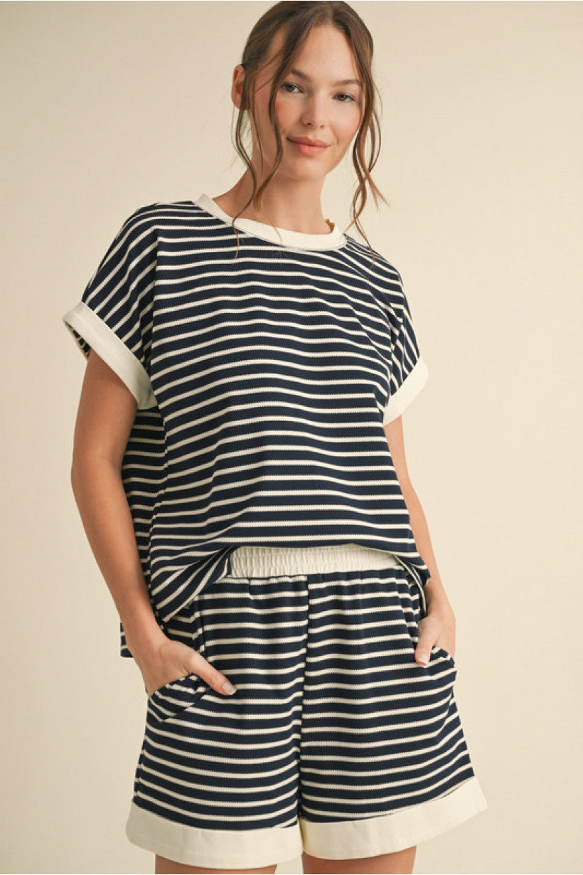 A two piece set with navy and white stripes. The top features a relaxed fit with a U-neckline, vented hem, and contrast ribbed trim. The matching shorts include an elastic waistband, side pockets, and cuffed hems 