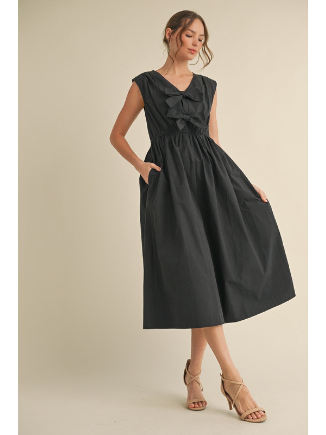 Black poplin midi dress with cap sleeve and two bows on the front.