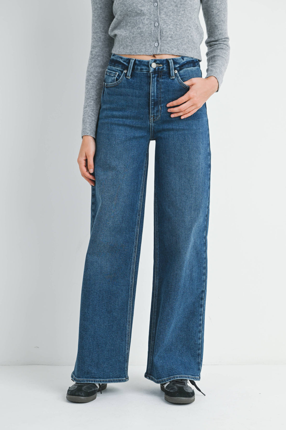 Person wearing blue jeans and a gray shirt on a plain background