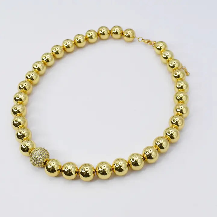necklace features large gold-plated beads and a beaded crystal ball centerpiece