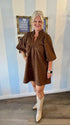 Brown lace-trimmed mini dress with leaf-print texture, ruffled neckline, and puff sleeves — styled with ivory cowboy boots for a chic fall look.