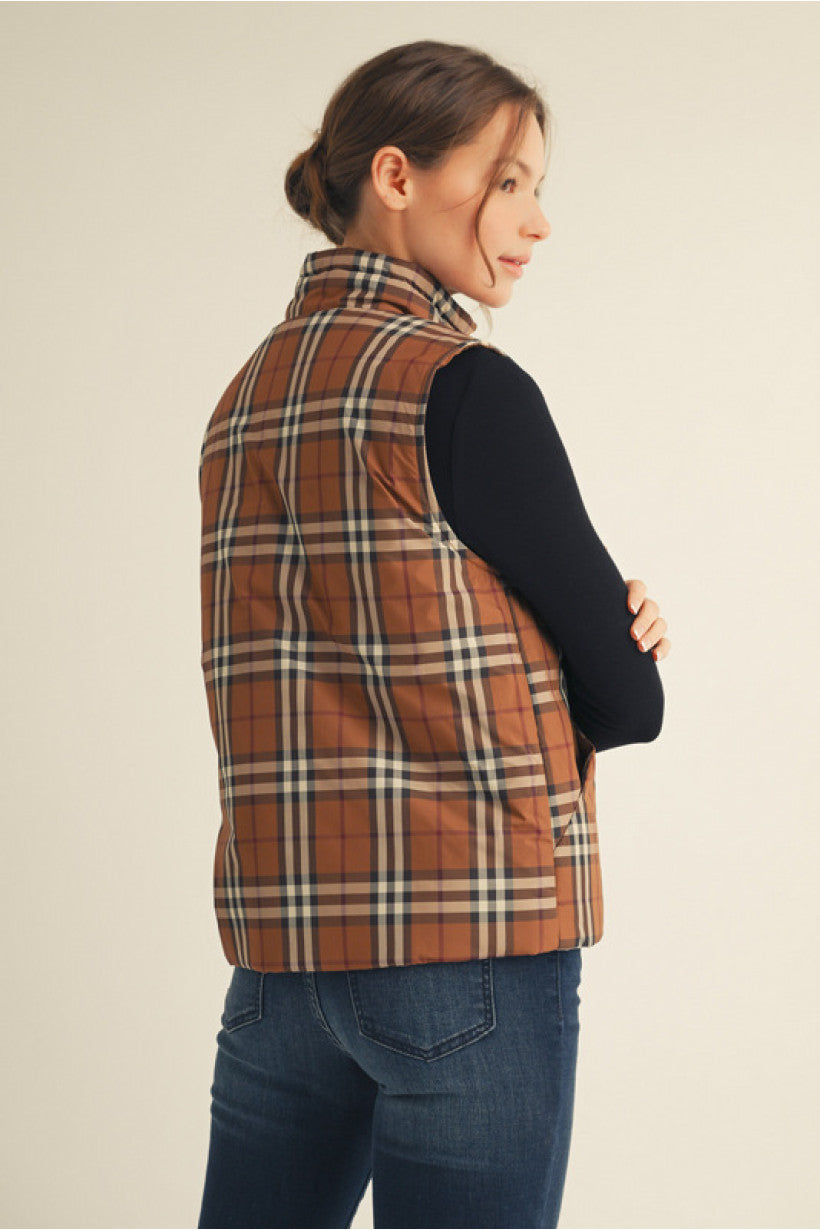Woman wearing a plaid vest over a black long-sleeve shirt on a beige background