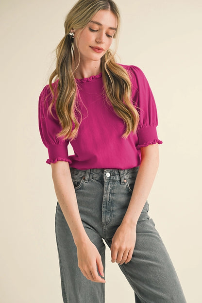 Woman wearing a bright pink blouse and gray jeans on a beige background