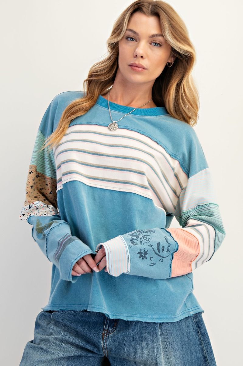 Woman wearing a blue and white striped sweater with floral sleeves on a plain background