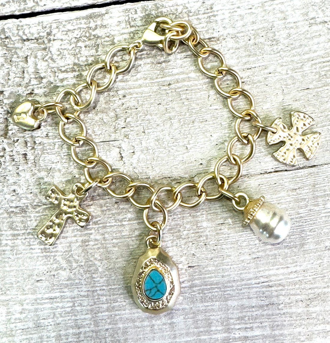 matte gold-plated charm bracelet features delicate cross charms, luminous pearls, and vibrant turquoise accents