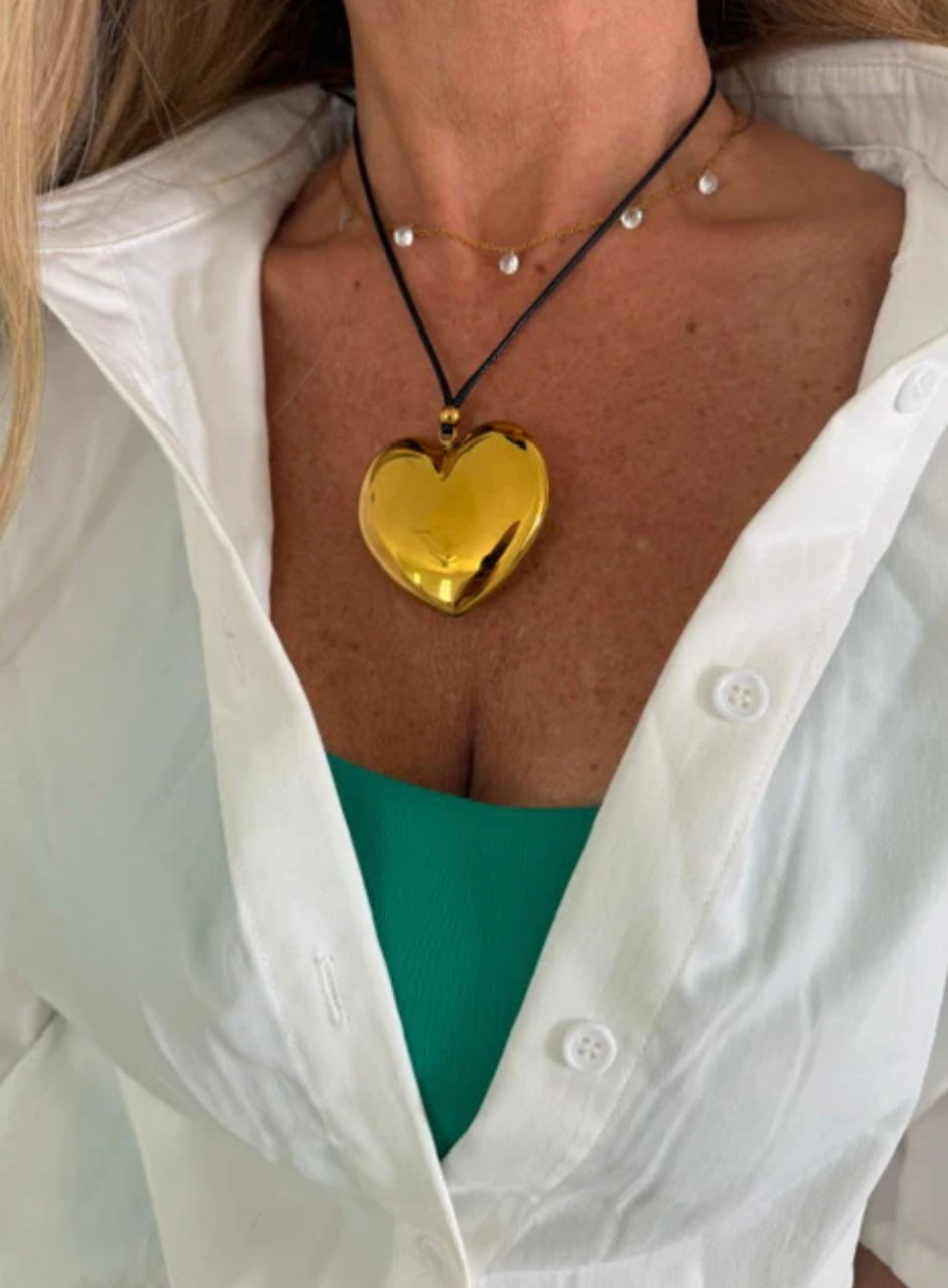 large, gold, shiny heart charm on a sleek black cord necklace 