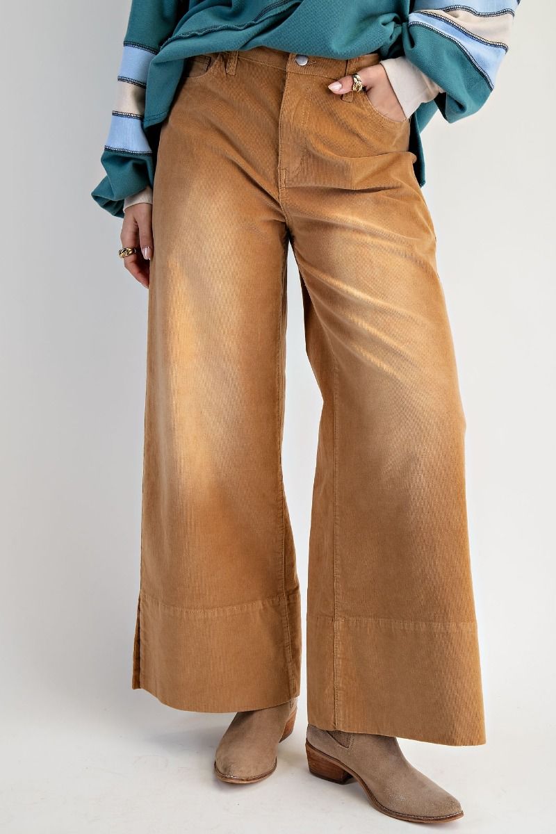 Brown corduroy pants worn with a teal shirt on a white background