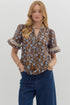 charming blouse features a rich brown background adorned with delicate blue floral prints, accented by pleated ruffle trim on the sleeves and neckline