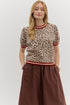 Featuring a classic leopard print in soft neutral tones, this top is elevated with bold red and ivory striped trim at the neckline, sleeves, and hem