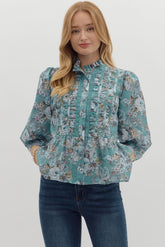 soft teal background, romantic rose print, and rows of ruffle and lace detailing down the front, this blouse brings major vintage vibes with a modern flair