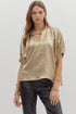 Woman wearing a metallic gold crinkle-textured blouse with a V-neckline and gathered short sleeves, paired with black leather pants against a light background