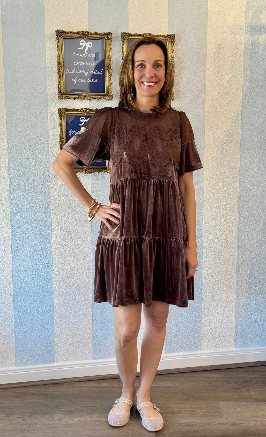 Woman wearing mocha velvet tiered dress with embroidered lace bodice and short sleeves, styled with gold bracelets and blush flats.