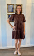 Woman wearing mocha velvet tiered dress with embroidered lace bodice and short sleeves, styled with gold bracelets and blush flats.