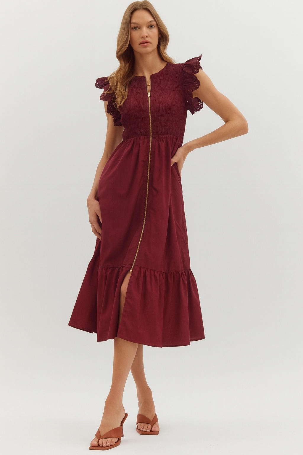 Burgundy midi dress with eyelet flutter sleeves, smocked bodice, front gold zipper, and tiered hemline.