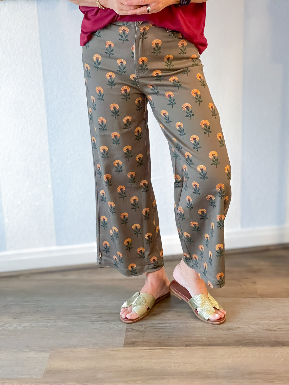 Person wearing gray pants with a floral pattern and sandals indoors.