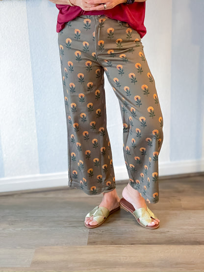 Person wearing gray pants with a floral pattern and sandals indoors.