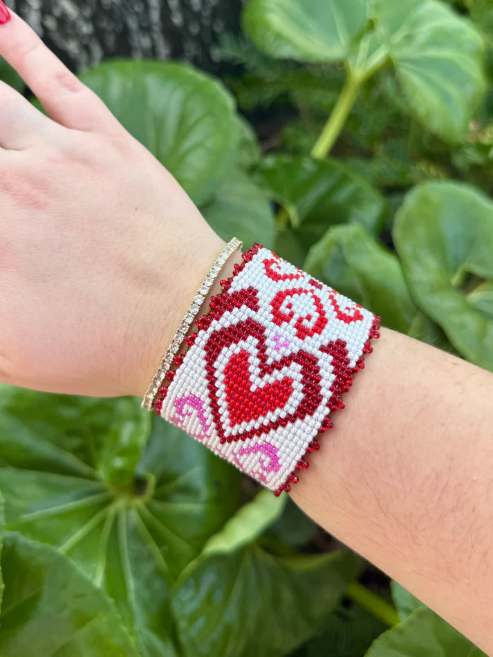 Cuff with bead pattern full of hearts in varying shapes and sizes with accent curls, and a delicate crystal red-beaded trim