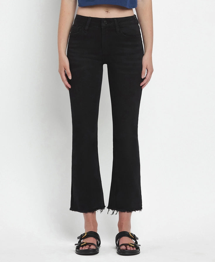 Person wearing black flared jeans on a white background