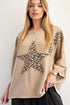 Woman wearing a beige sweater with a leopard print star design on a white background