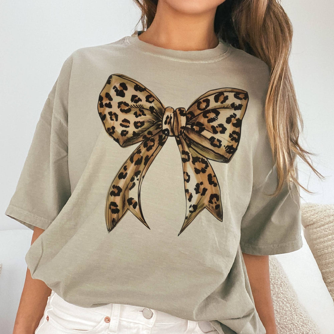 Person wearing a beige t-shirt with a leopard print bow design.