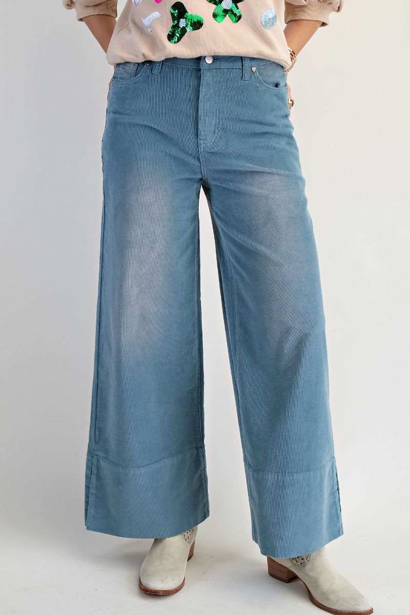 Person wearing blue wide-leg jeans on a plain background