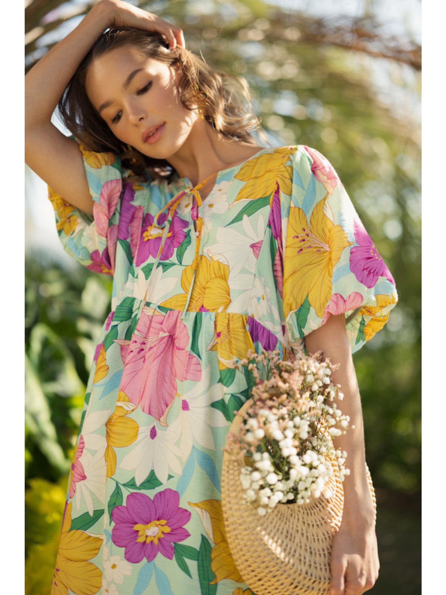 A dress with a tie neckline and puffed half sleeves. Featuring a vibrant floral print in a mix of bold and pastel hues.