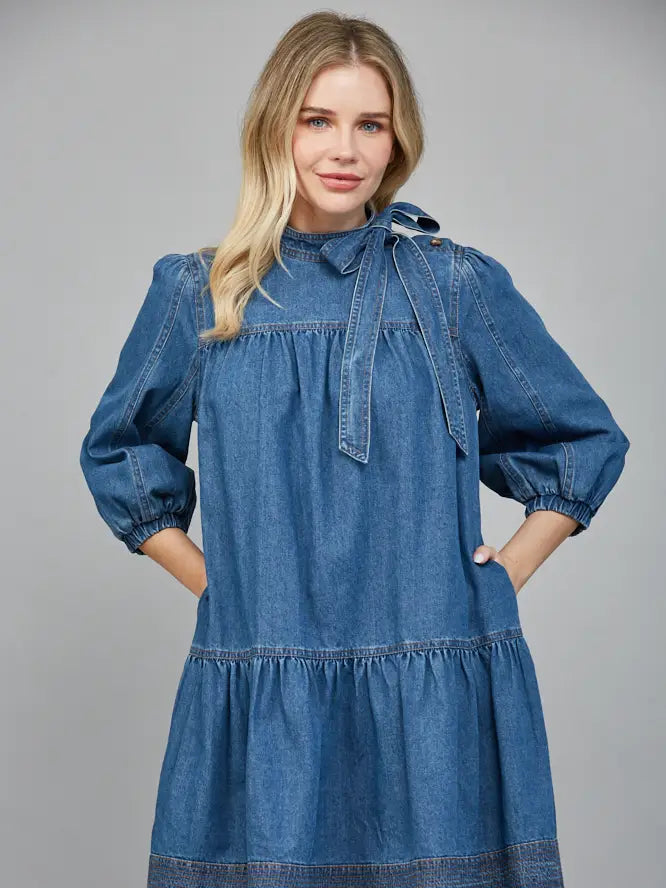 Woman wearing a blue denim dress against a gray background